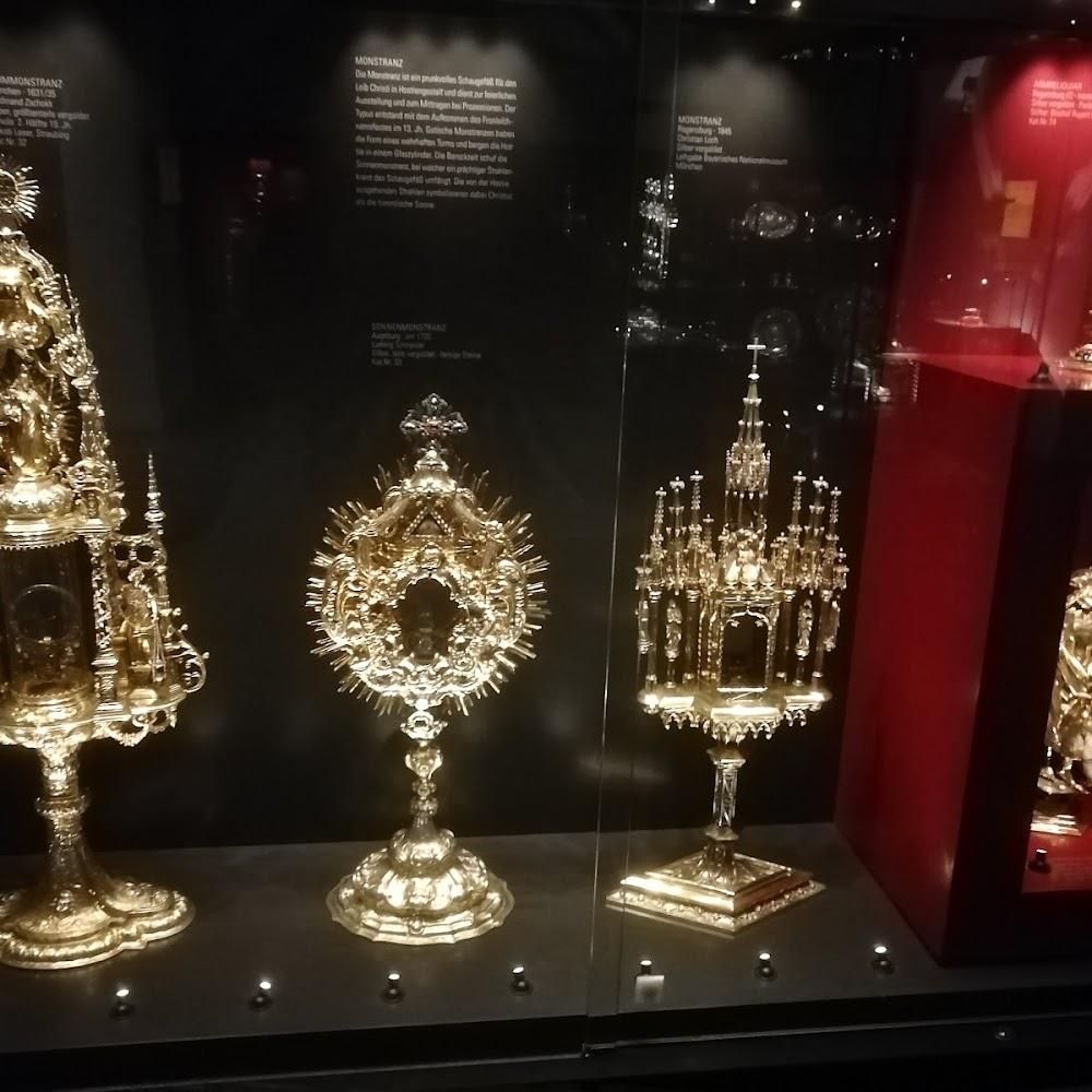 Three gold monstrances on display in a glass case.